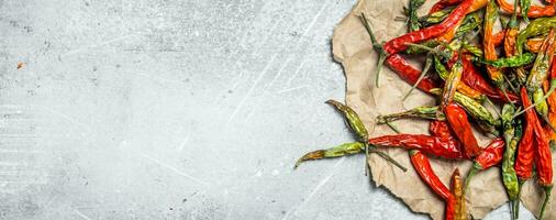 Dried hot pepper pods on paper. photo