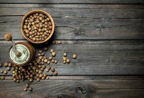 Pepper peas in bowl and pepper grinder. photo