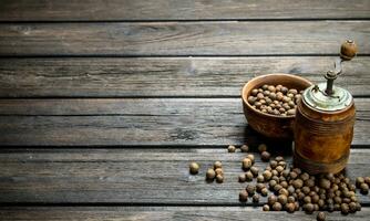 Pepper peas in bowl and pepper grinder. photo