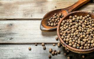 Black pepper in a bowl and spoon. photo