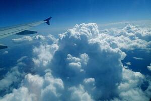 white clouds against the blue sky seen from the flight from the windows of the plane photo