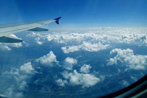 white clouds against the blue sky seen from the flight from the windows of the plane photo