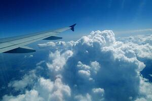 white clouds against the blue sky seen from the flight from the windows of the plane photo