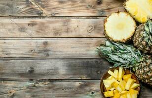 Slices of pineapple in a bowl and fresh pineapple. photo