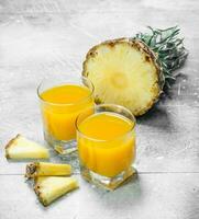 Pineapple juice in a glass and slices of ripe pineapple. photo