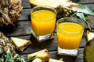 Pineapple juice in a glass and pieces of fragrant pineapple. photo