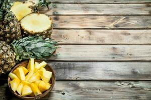 Slices of pineapple in a bowl and fresh pineapple. photo