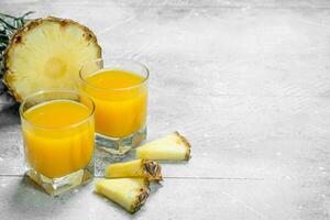 Pineapple juice in a glass and slices of ripe pineapple. photo