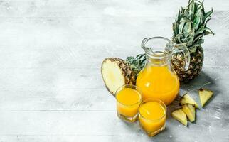 Pineapple juice in a glass jug and fresh pineapple. photo