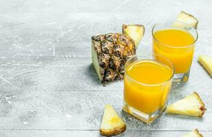 Pineapple juice in a glass and slices of fragrant pineapple. photo