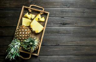 Whole and slices of ripe pineapple on a tray. photo