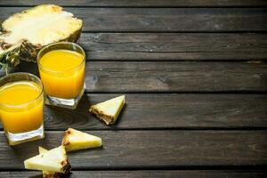 Pineapple juice in a glass and slices of fresh pineapple. photo