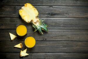 Pineapple juice in a glass and slices of fresh pineapple. photo