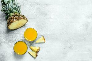 Pineapple juice in a glass and slices of ripe pineapple. photo