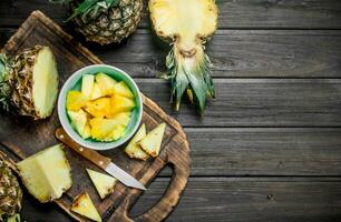 cortar un piña en un cuenco y en un corte tablero con un cuchillo. foto