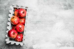 Red pomegranates in a plastic box. photo