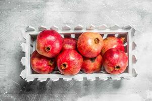 Red pomegranates in a plastic box. photo