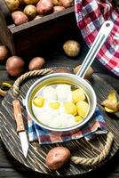 Potatoes in a saucepan with napkin and a knife on tray. photo