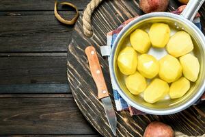 Potatoes in a saucepan with napkin and a knife on tray. photo