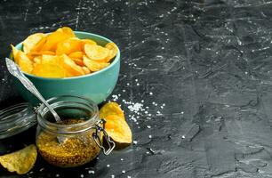 Potato chips in a bowl with mustard. photo