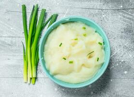 Mashed potatoes in a bowl with green onions. photo