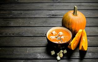 Pumpkin soup in bowl with rusks and whole pumpkin. photo