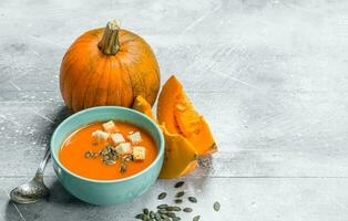 calabaza sopa en un cuenco con un cuchara y piezas de Fresco calabaza. foto