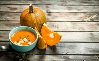 Pumpkin soup in bowl with spoon and fresh pumpkin. photo