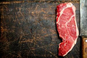 Raw beef steak with hatchet. photo