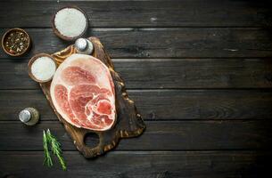 Big raw pork steak with rosemary on cutting Board. photo