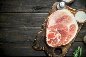 Big raw pork steak with rosemary on cutting Board. photo