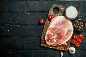 Big raw pork steak with tomatoes and spices. photo