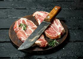 Raw pork steak with an old knife on a cutting Board. photo