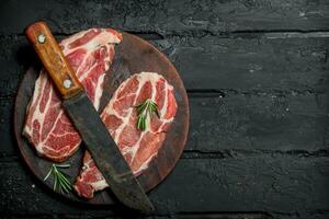 crudo Cerdo filete con un antiguo cuchillo en un corte tablero. foto