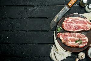 Raw pork steak with an old knife on a cutting Board. photo