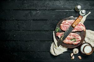 Raw pork steak with an old knife on a cutting Board. photo