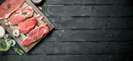 Raw meat. Pork and beef steaks on a tray with spices and rosemary sprig. photo