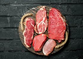 Raw meat. Beef and pork steaks on a wooden tray. photo
