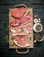 Raw meat. Pork and beef steaks on a tray with spices and rosemary sprig. photo