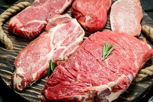 Raw meat. Beef and pork steaks on a wooden tray. photo