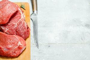 Raw meat.Pieces of fresh beef with rosemary branches. photo