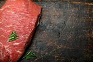 Raw meat. A piece of beef with rosemary. photo