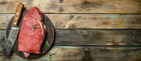 Raw meat. A piece of fresh beef with a hatchet on an old cutting Board. Raw meat. photo