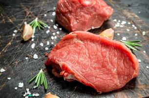 Raw meat. Pieces of fresh beef with salt and rosemary. photo