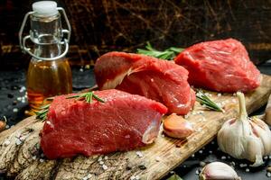 Raw meat. Pieces of fresh beef with spices, garlic and rosemary. photo
