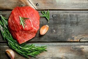 Raw meat. A piece of beef with rosemary and garlic. photo