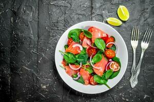 Fish salad. Salad with slices of salmon, tomatoes and spinach with lime juice. photo