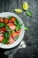 Fish salad. Salad with slices of salmon, tomatoes and spinach with lime juice. photo