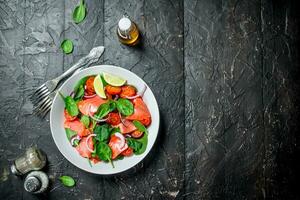 Fish salad. Salad with slices of salmon, tomatoes and spinach with lime juice. photo