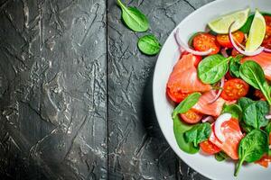 Fish salad. Salad with slices of salmon, tomatoes and spinach with lime juice. photo